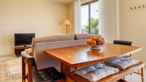 Una sala de estar moderna con un sofá, una mesa de comedor de madera, un televisor y un frutero.