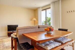 Ein modernes Wohnzimmer mit einer Couch, einem Holzesstisch, einem Fernseher und einer Obstschale.
