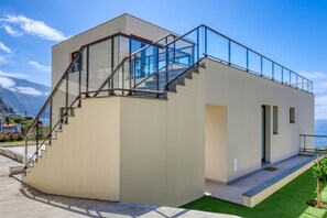 A modern building with a glass staircase, a flat roof, and a view of the sea. - Casa da Mercês II, a Home in Madeira (São Vicente)