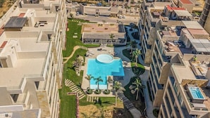 Ein Hochhaus mit Dachpool, mehreren Balkonen und einem zentralen Innenhof mit Palmen.