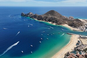 An aerial view of a coastal area with boats, a beach, and buildings. - Spectacular Vista Vela Condos - Near Major Attractions, AC & Balcony Grill (Cabo San Lucas)