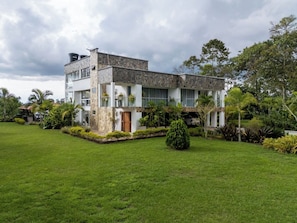A two-story house with a stone facade, a wooden door, and a well-maintained lawn.