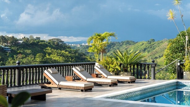 Zona de piscina en la azotea con sillones de descanso y vistas a un paisaje exuberante.