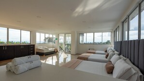 Una habitación de hotel moderna con una cama grande, una cama más pequeña, un sofá, un armario y un balcón con vistas.
