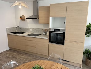 Eine moderne Küche mit Holzschränken, einem schwarzen Backofen und einer Edelstahl-Dunstabzugshaube.