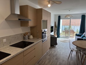 Eine moderne Küche mit Holzausstattung, einem eingebauten Ofen und einer Essecke mit rundem Tisch und Stühlen.