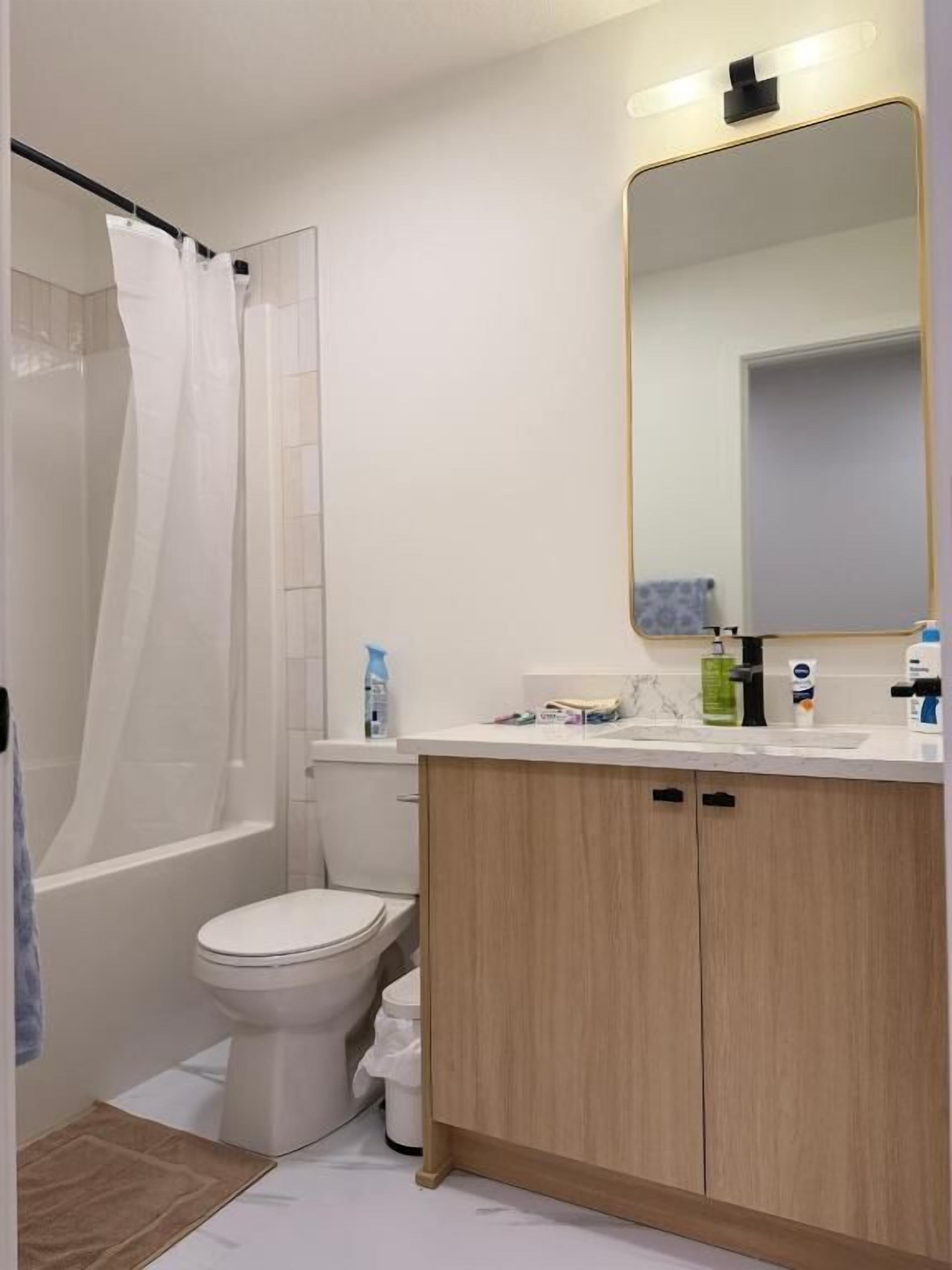 Een badkamer met een douche, toilet en wastafel met spiegel.