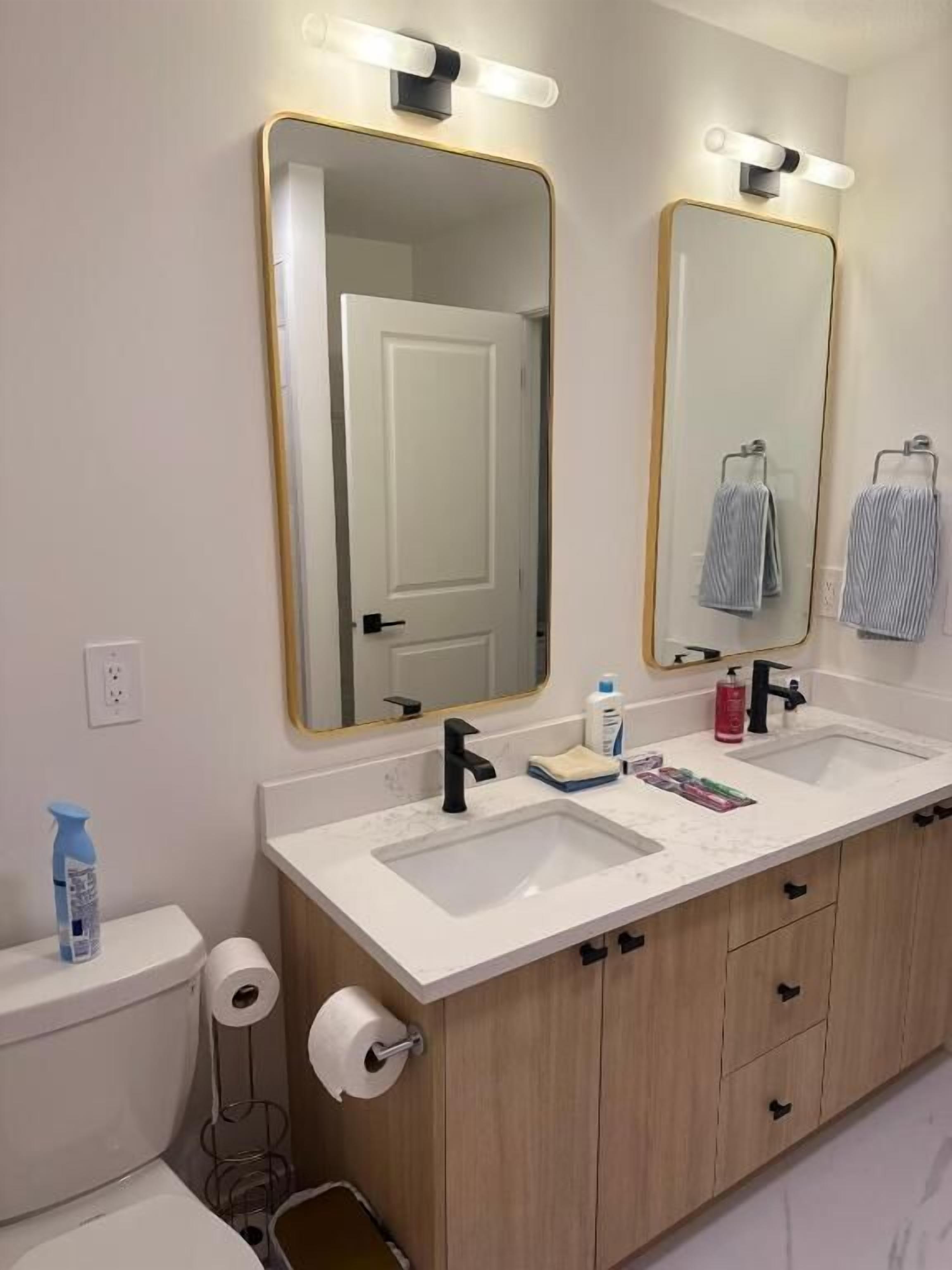 A bathroom with two sinks, a toilet, a mirror, and a towel rack.
