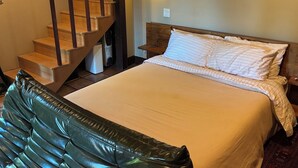 A bedroom with a bed, a wooden staircase, a nightstand, and a wall-mounted light. - Charming furnished "Tree House" in the Hollywood Hills with views and parking. (Los Angeles)