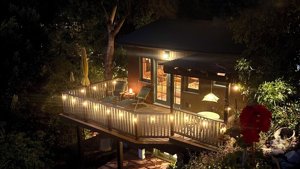 A wooden deck with outdoor seating and a glass enclosure. - Charming furnished "Tree House" in the Hollywood Hills with views and parking. (Los Angeles)