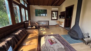 A spacious living room with a large sofa, a dining table, and a fireplace. - Charming furnished "Tree House" in the Hollywood Hills with views and parking. (Los Angeles)