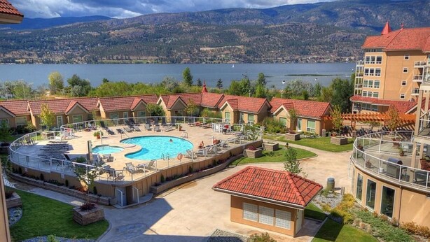Un hôtel doté d’une piscine, d’un espace extérieur aménagé et offrant une vue sur un lac et des montagnes.