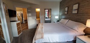 Ein Hotelzimmer mit Bett, Nachttisch, Lampe und Spiegel.