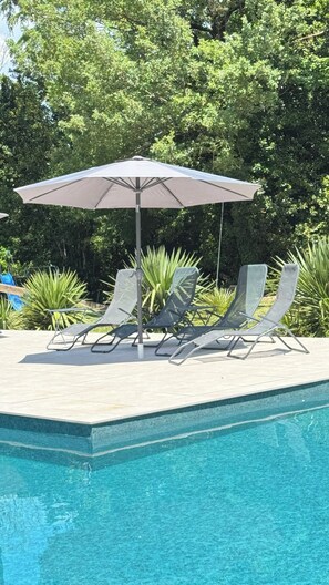 Ein Poolbereich mit Liegestühlen und Sonnenschirm.