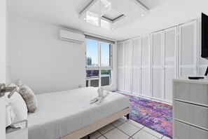 Una habitación de hotel moderna con cama, armario, televisor y ventana con persianas.