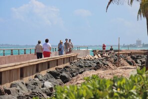 Eine Promenade mit Menschen, die darauf entlanggehen, mit Blick auf ein Gewässer.