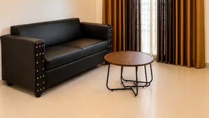 Ein modernes Zimmer mit einer schwarzen Ledersofa, einem runden Holztisch und einem Deckenventilator.