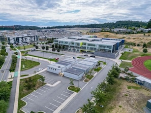 A modern building with a parking lot, a running track, and a green space. - The Royal Bay Stay,  by Victoria Prime! (Victoria)