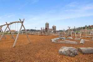 A playground with swings and climbing structures, surrounded by a gravel area. - The Royal Bay Stay,  by Victoria Prime! (Victoria)