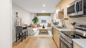 Cozinha moderna com micro-ondas, forno e pia. Possui um espaço de refeições com mesa e cadeiras.