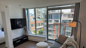 Una camera da letto moderna con una grande finestra, una TV a schermo piatto, un divano e un comodino.