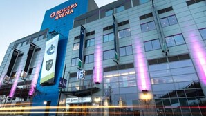 Un edificio moderno con un grande cartello con su scritto 'Rogers Arena' e una bandiera con un logo.