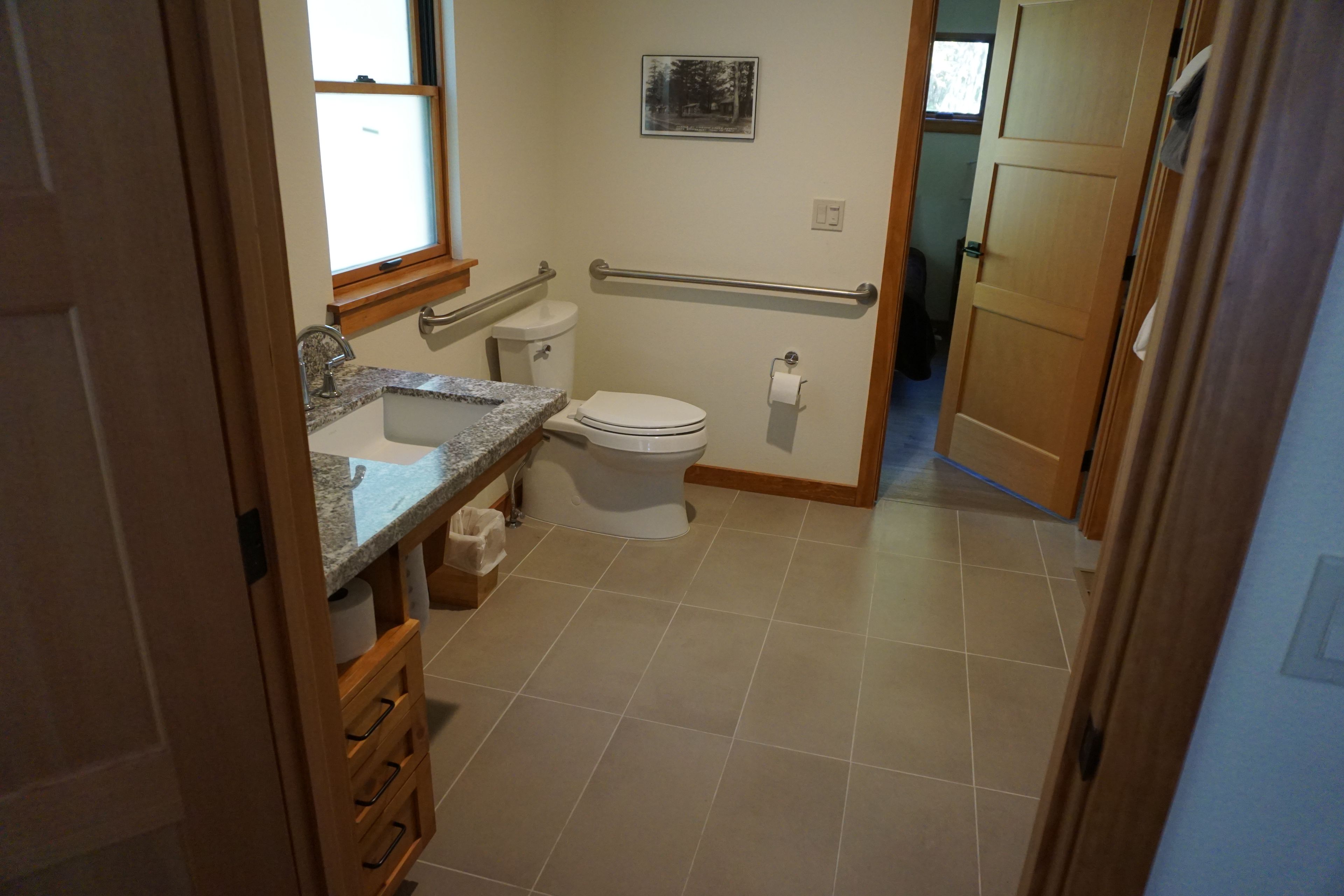 A bathroom with a toilet, sink, and a handrail.