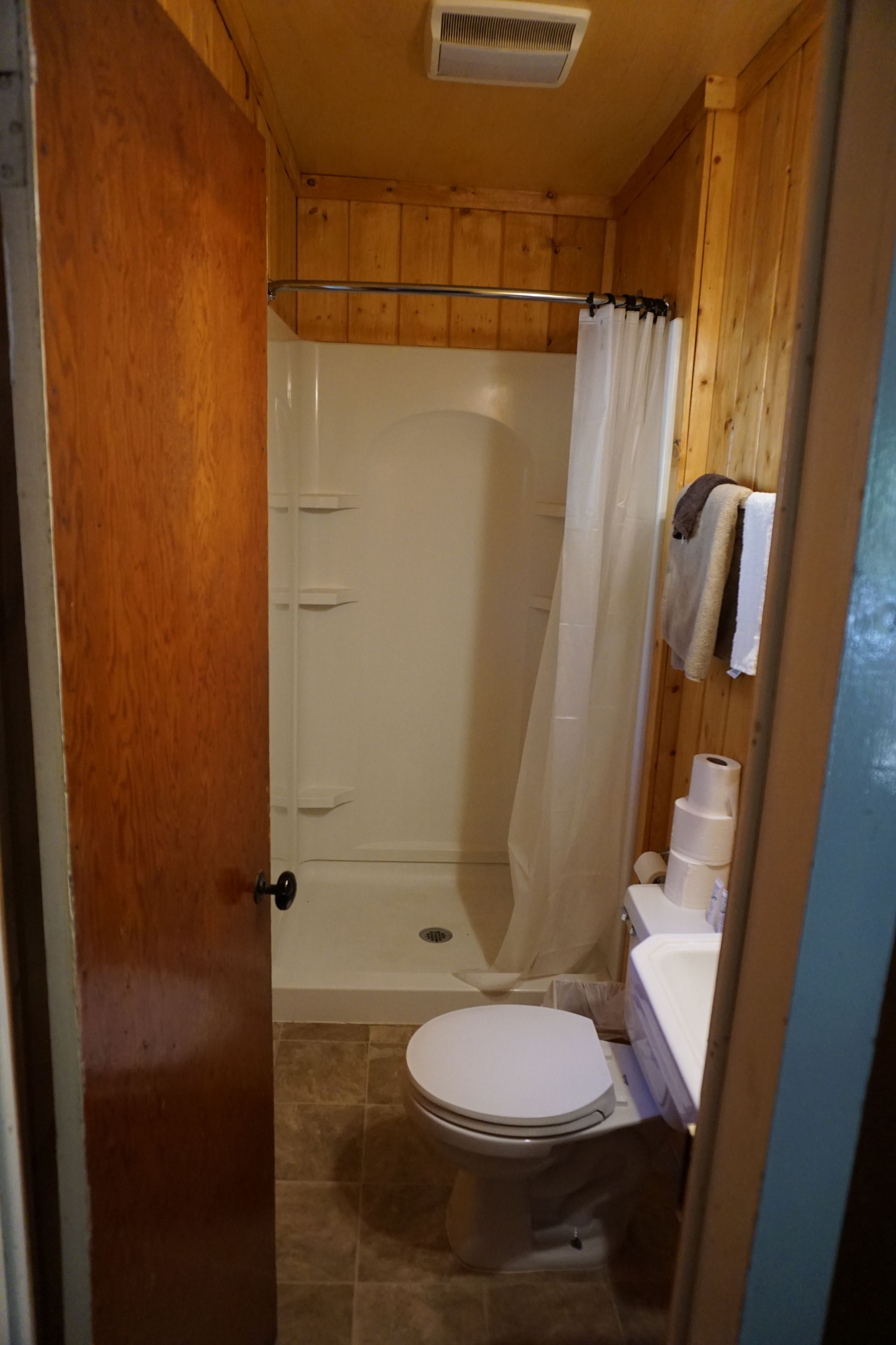 A bathroom with a shower, toilet, and a towel rack.