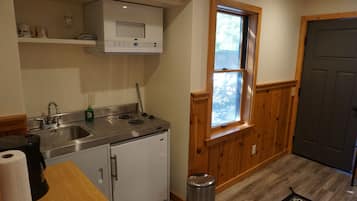 Una cocina compacta con microondas, estufa, lavaplatos y ventana con vistas.