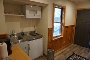 Una cocina compacta con microondas, estufa, lavaplatos y ventana con vistas.
