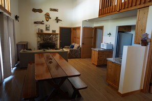A cozy living room with a wooden bench, a stone fireplace, and a dining table.