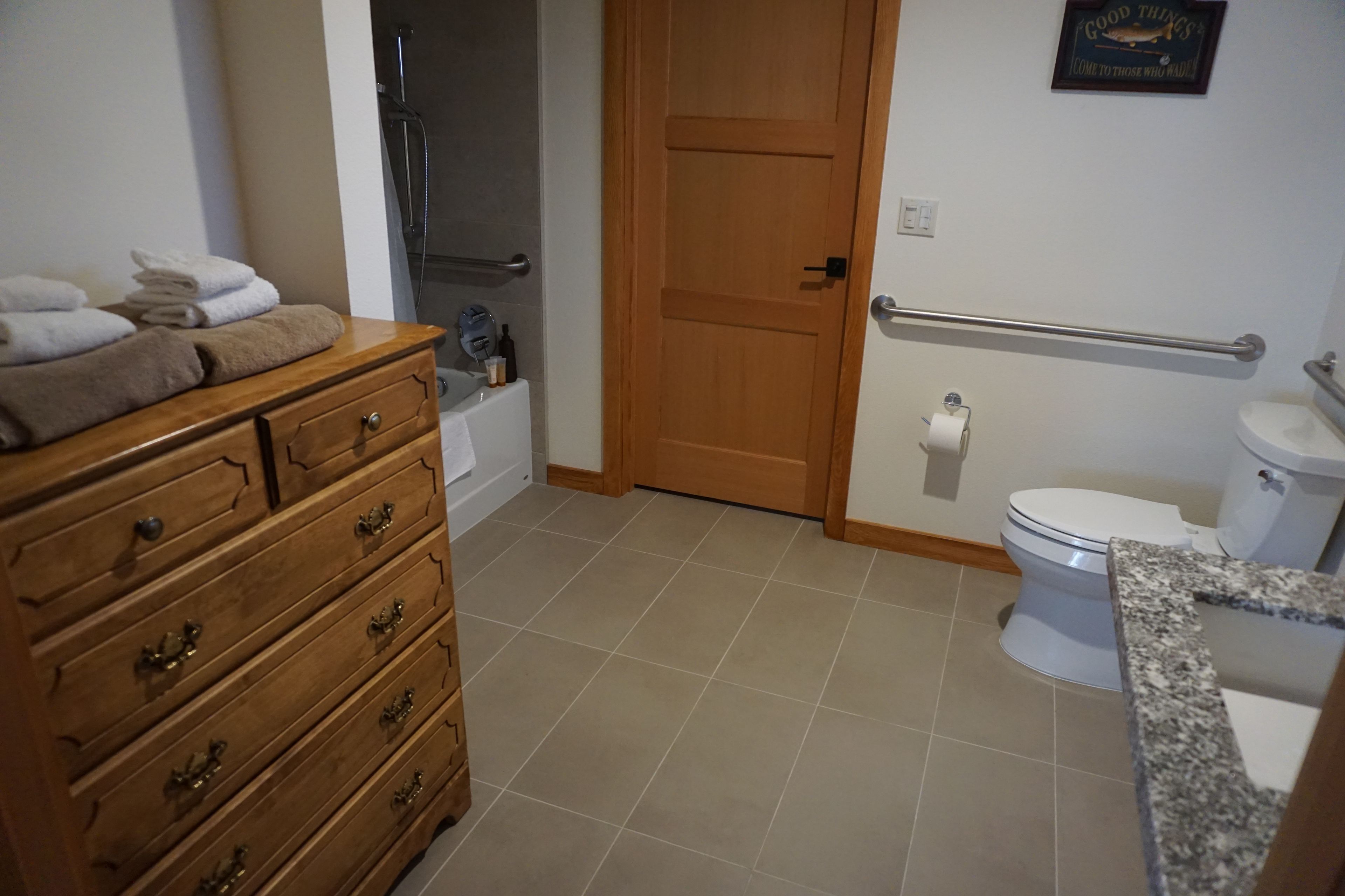 Une salle de bain avec un meuble-lavabo en bois, une baignoire, des toilettes et une douche.