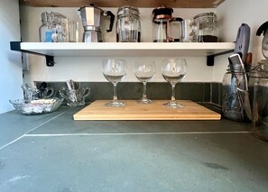 A kitchen counter with three wine glasses, a coffee maker, and a knife block.