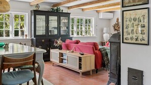 A dining area with a table and chairs, a black cabinet with glass doors, a red sofa, and a fireplace. - 4 Star Holiday Home in Harpelunde (Harpelunde)