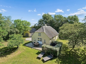 Ein zweistöckiges Haus mit Terrasse, einer kleinen Holzterrasse und einem gepflegten Rasen.