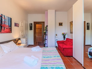 Ein Hotelzimmer mit einem Bett, einem roten Sofa, einer Holztür und einem Bild an der Wand.
