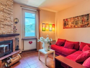 Ein Wohnzimmer mit Kamin, einem roten Sofa und einem Gemälde an der Wand.