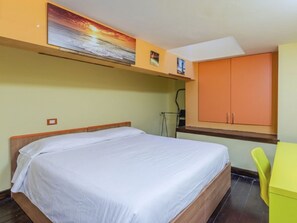 Ein Schlafzimmer mit einem Bett, einem gelben Sessel und einem Schrank.