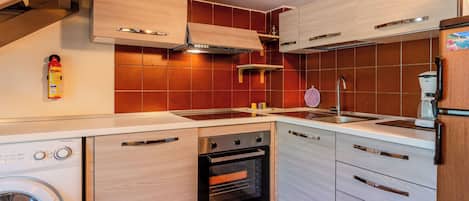 Uma cozinha compacta com máquina de lavar, forno e cafeteira.