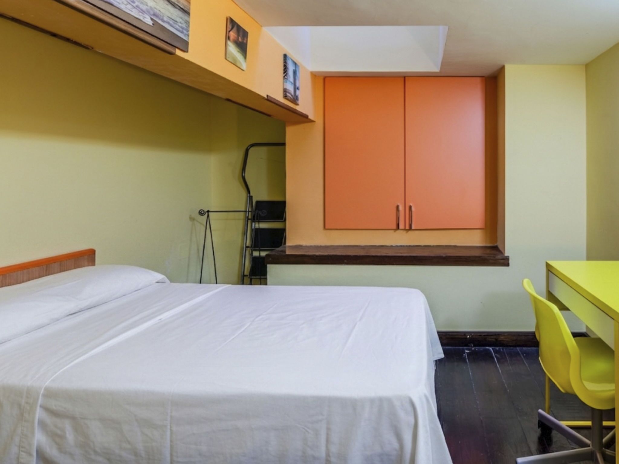 A room with a bed, a desk, a chair, and a wardrobe.