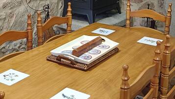 Een houten eettafel met stoelen, een open haard en stenen muren.