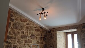 A room with stone walls, a ceiling fan, and a light fixture.