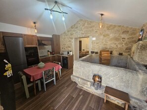 A rustic interior with a stone wall, wooden furniture, and a dining area.