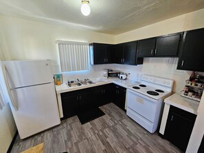 A kitchen with a refrigerator, stove, microwave, and black cabinets.