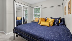 Ein Schlafzimmer mit Himmelbett, begehbarem Kleiderschrank und einem Fenster mit Jalousien.