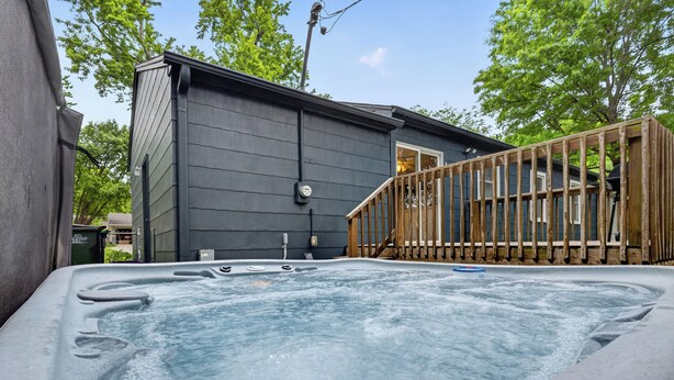 Ein Whirlpool vor einem Haus mit einer Holzterrasse und einem Fenster.