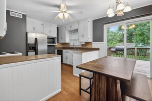 Una cocina moderna con armarios blancos, encimera de madera, una isla central y un ventilador de techo.