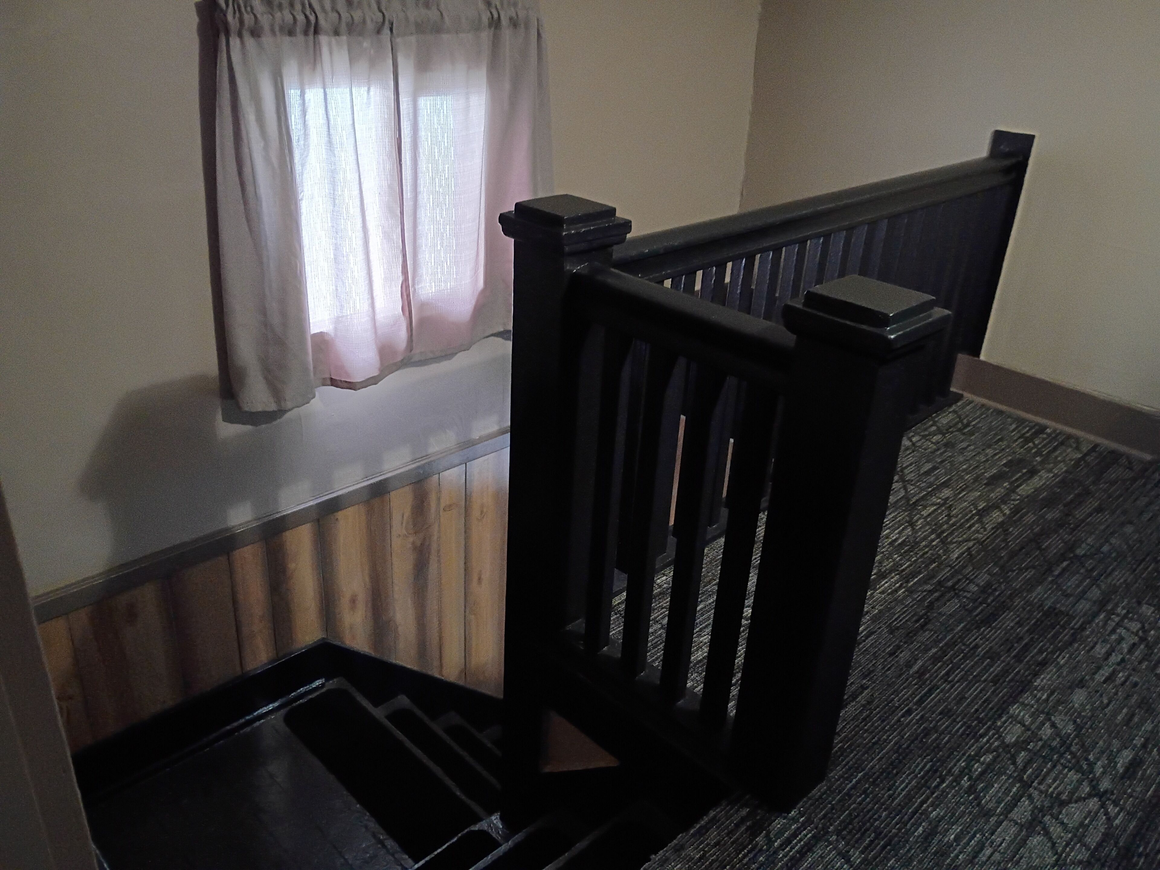 A staircase with a wooden handrail and a carpeted landing.