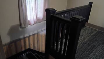 A staircase with a wooden handrail and a carpeted landing.