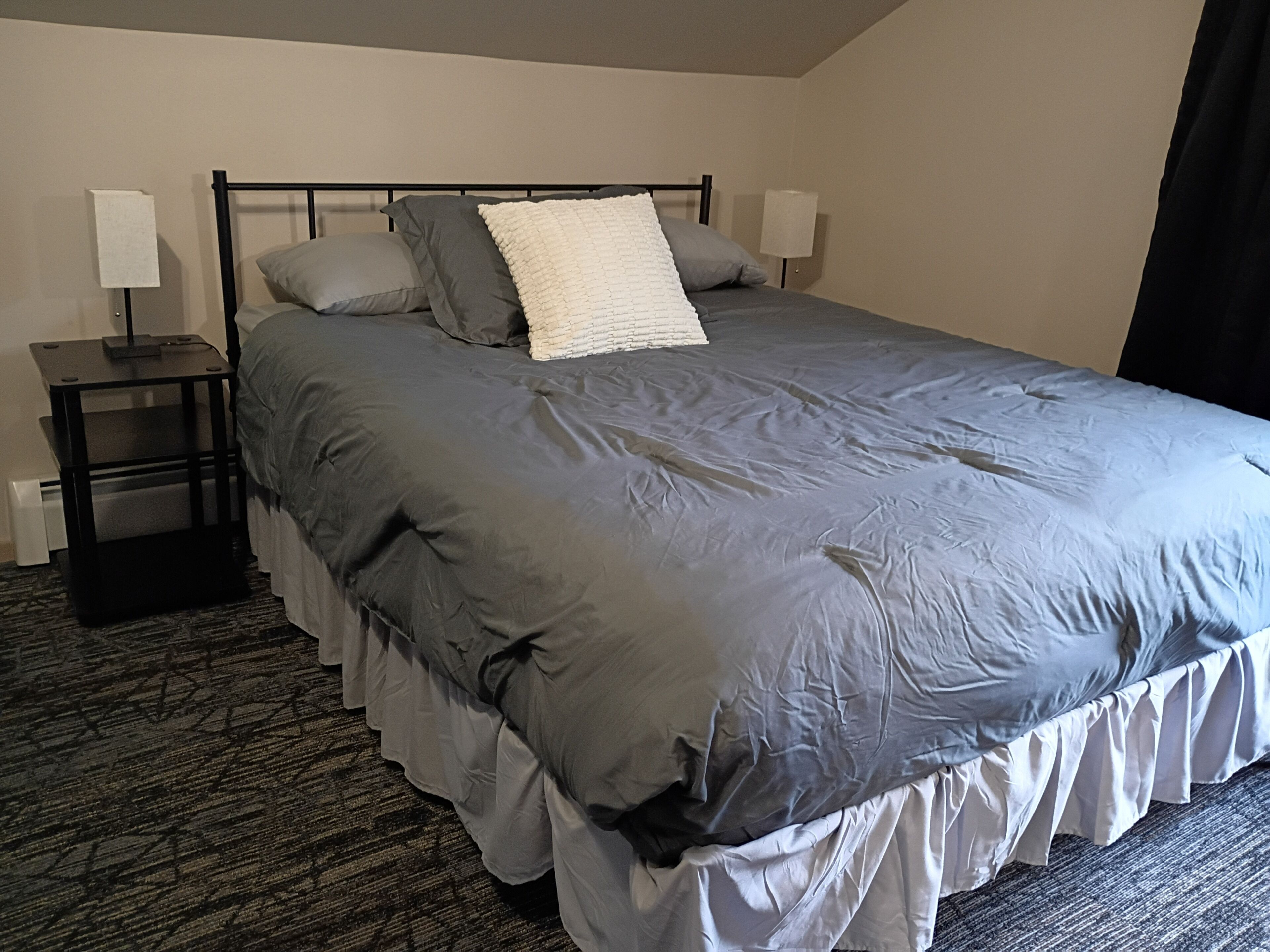 Une chambre d’hôtel avec un lit, deux tables de chevet et un sol recouvert de moquette.